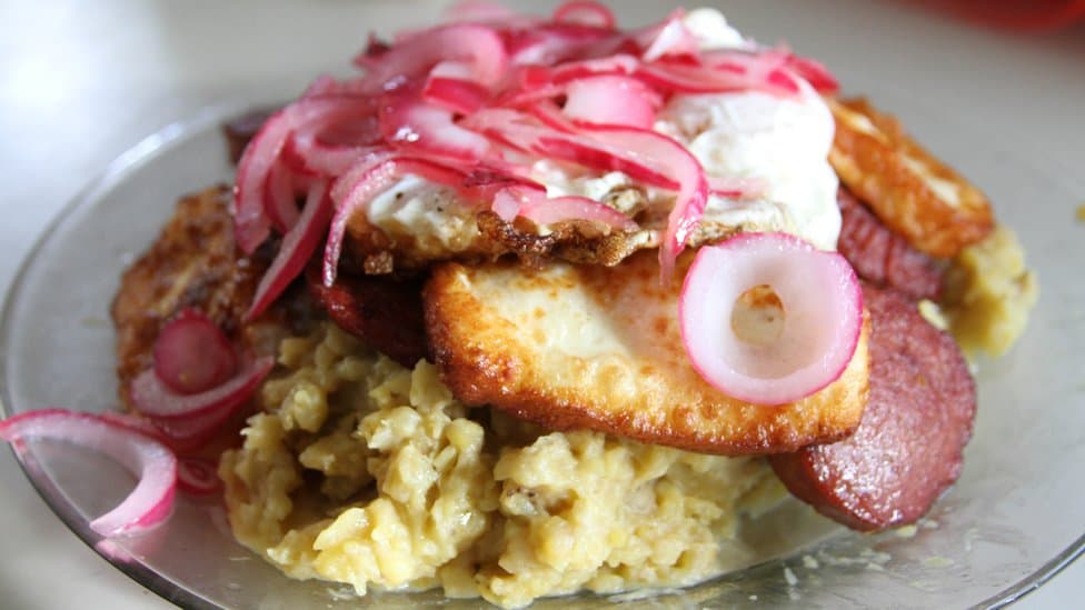 Mangú dominicano con huevo frito, salami, queso frito y cebolla roja encurtida.